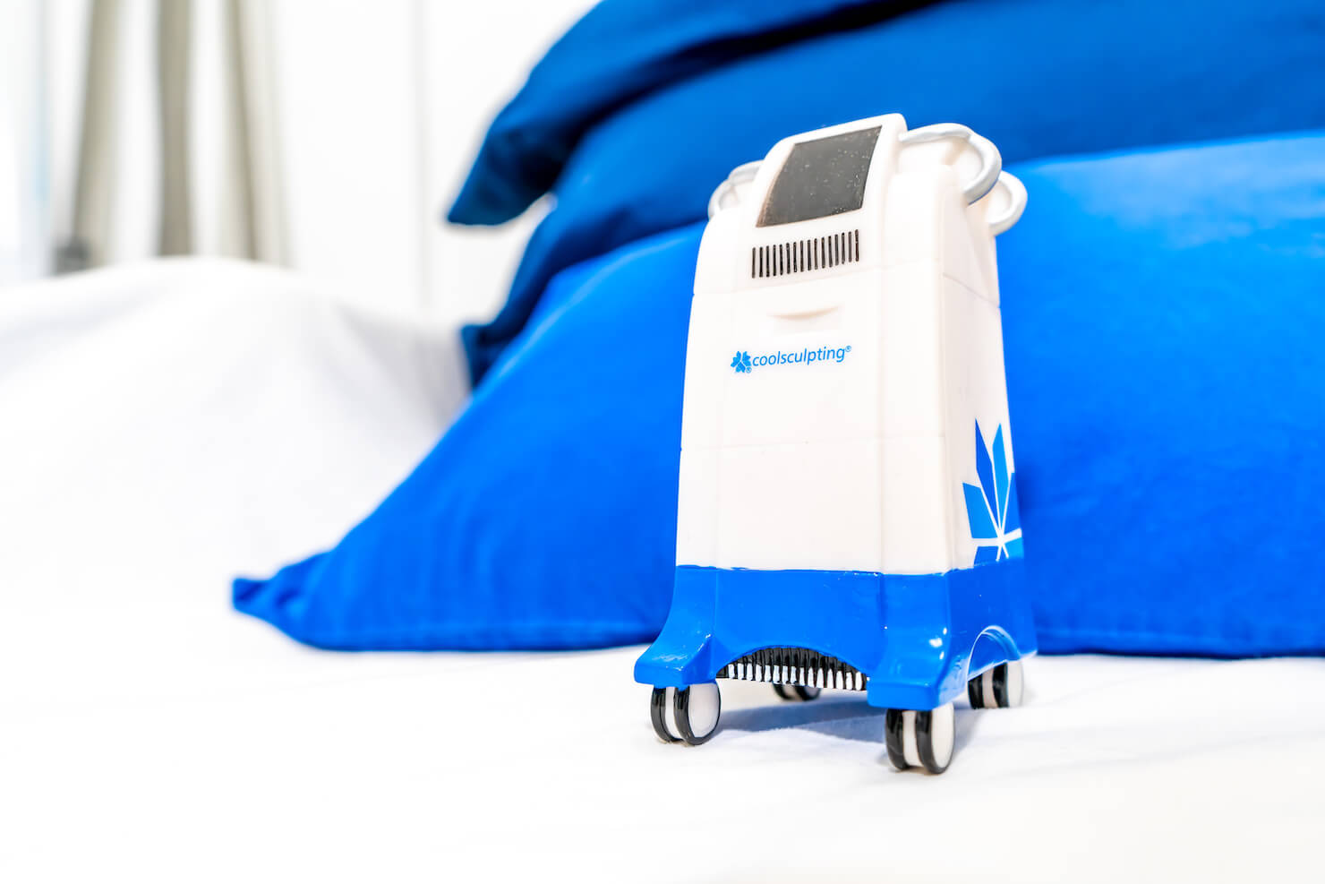 Miniature CoolSculpting machine model on branded bed for fat freezing treatments in Surrey